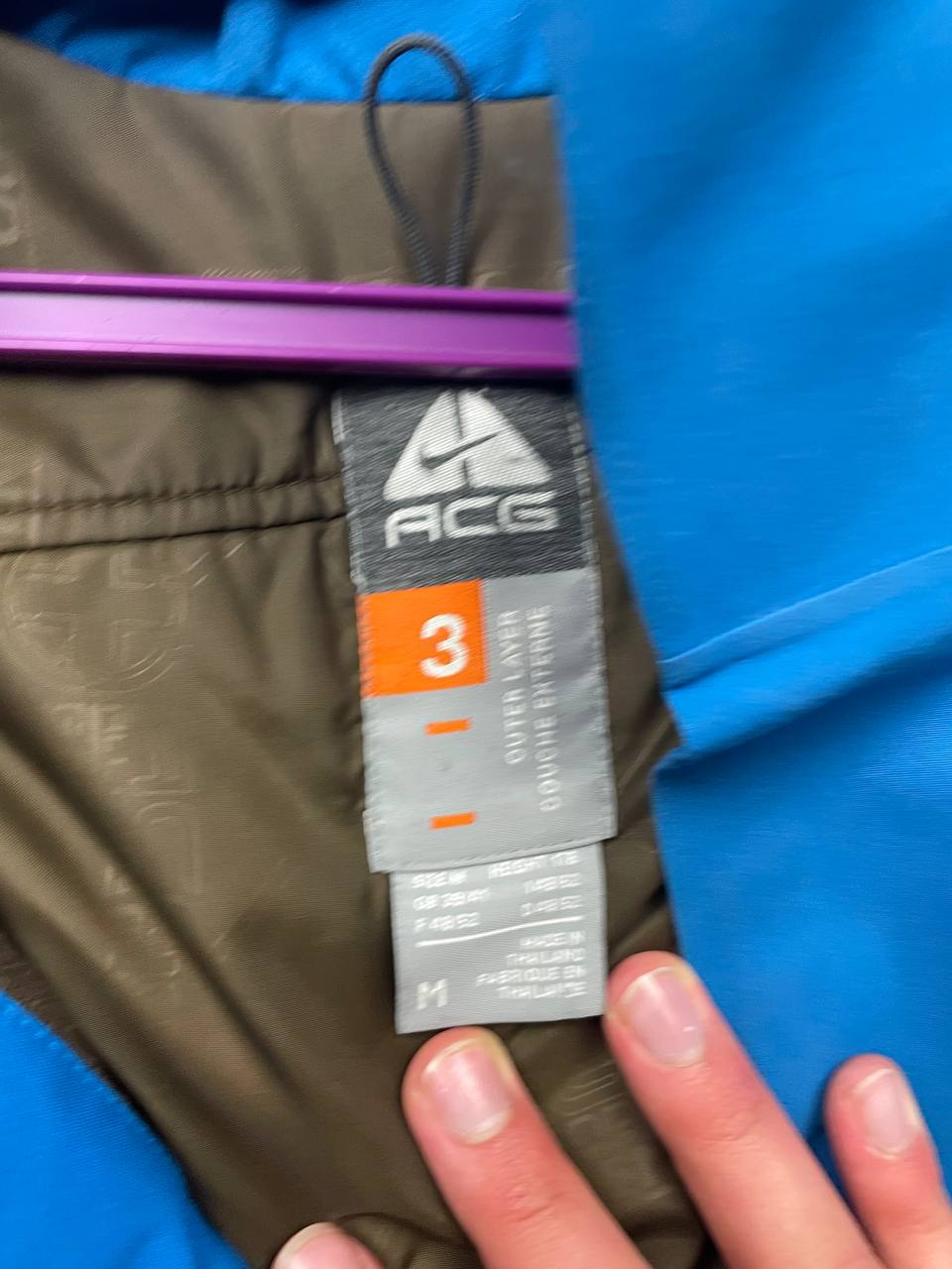 Nike ACG blue and brown waterproof jacket with Gore-Tex label and adjustable hood.