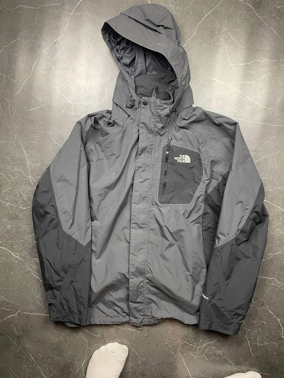 The North Face black and grey waterproof jacket with hood and chest pocket.