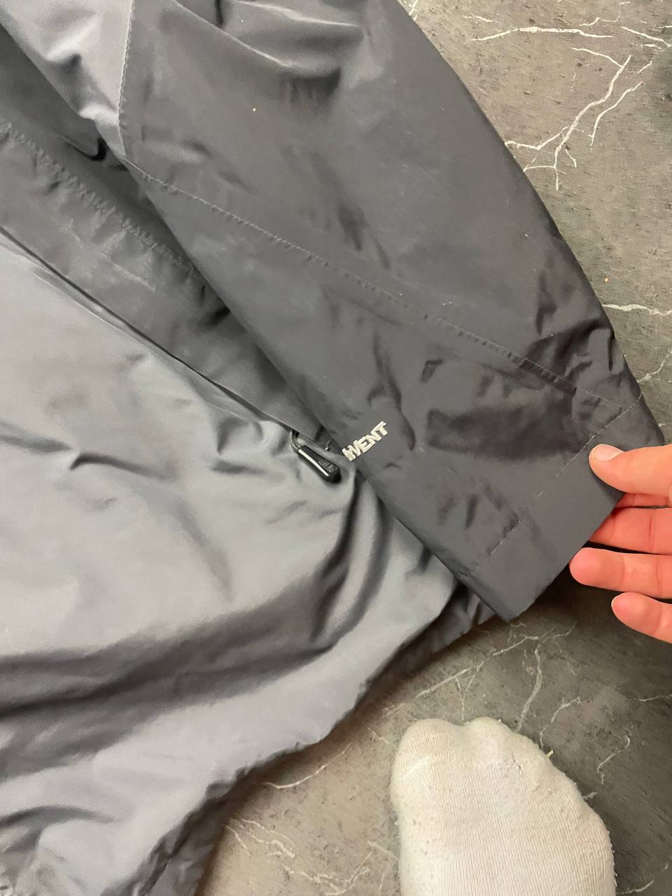 The North Face black and grey waterproof jacket with hood and chest pocket.