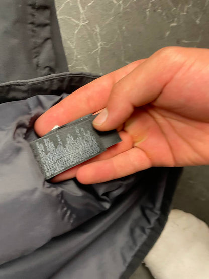 The North Face black and grey waterproof jacket with hood and chest pocket.