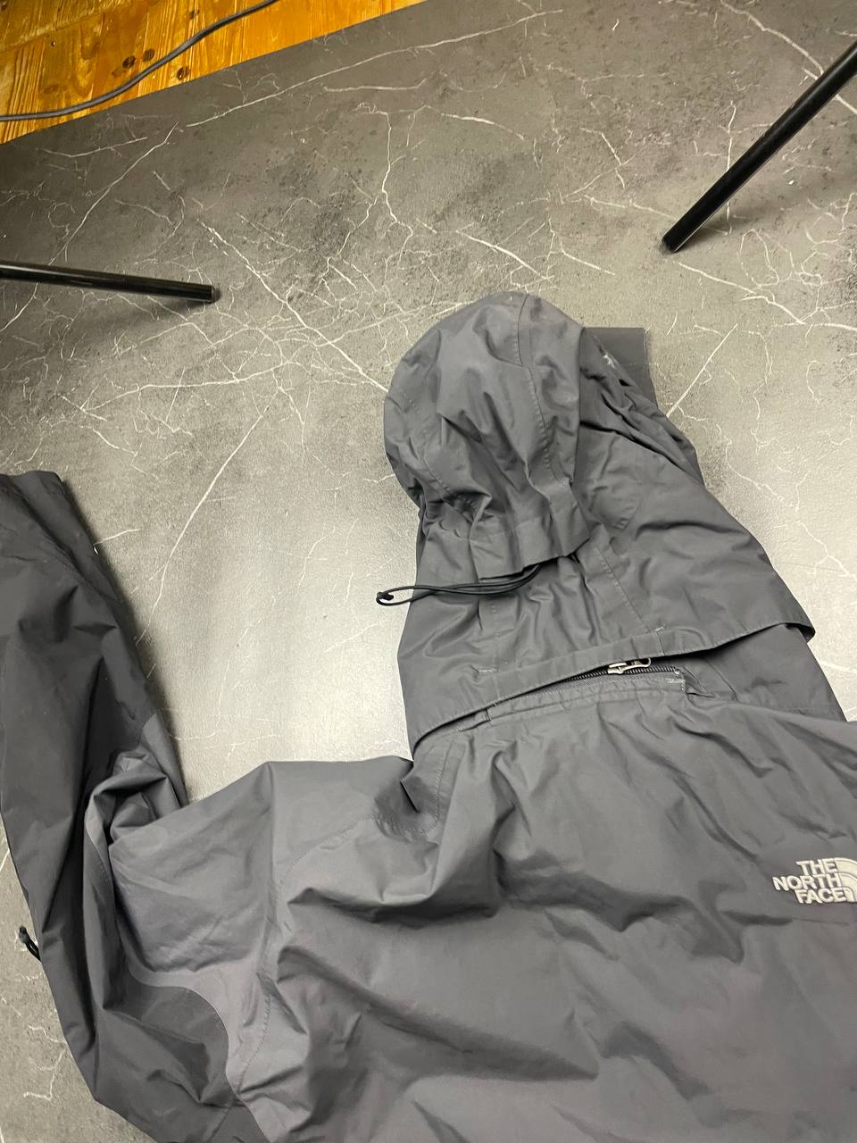 The North Face black and grey waterproof jacket with hood and chest pocket.