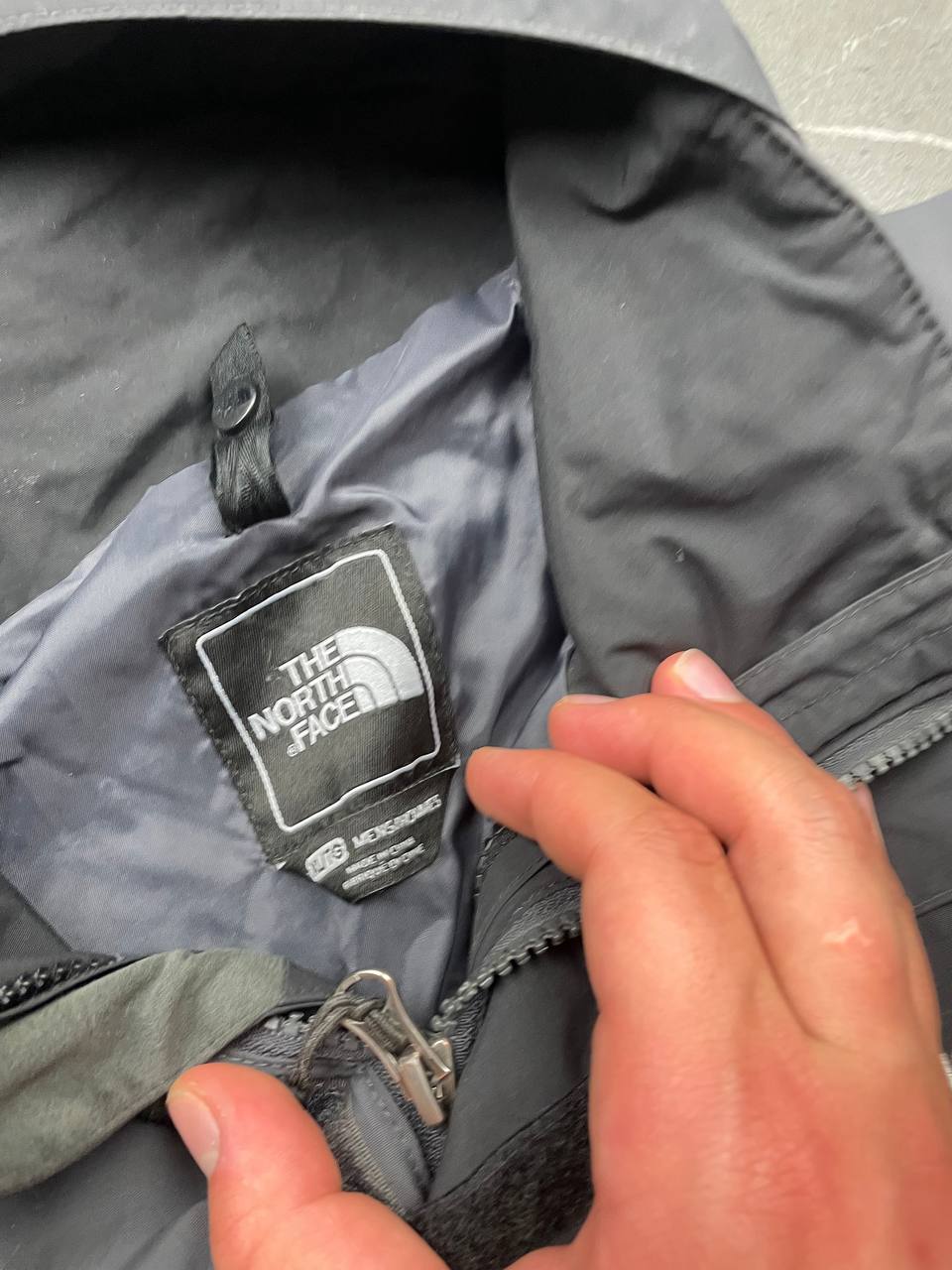 The North Face black and grey waterproof jacket with hood and chest pocket.