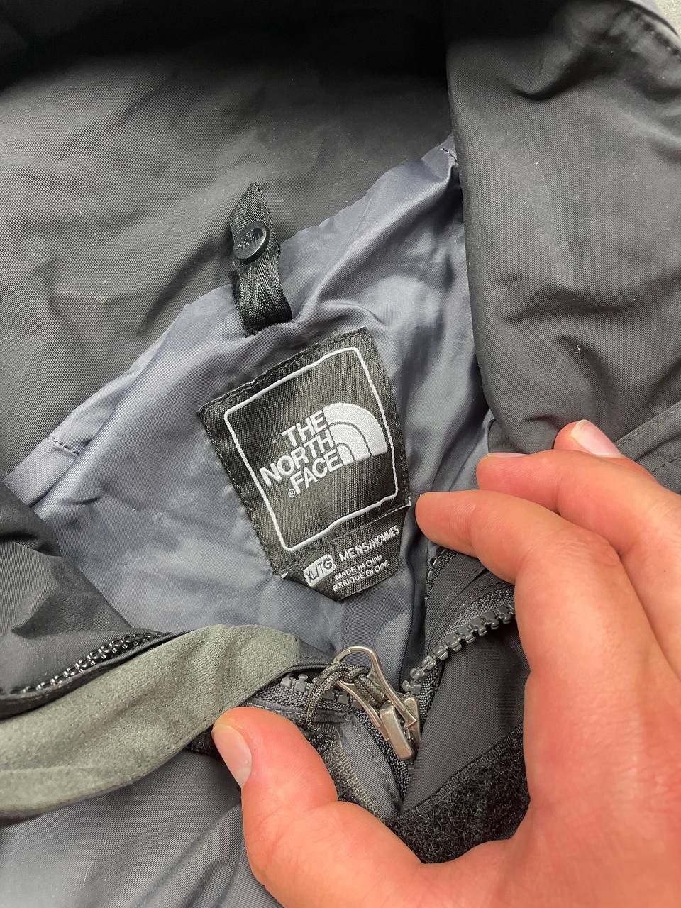 The North Face black and grey waterproof jacket with hood and chest pocket.