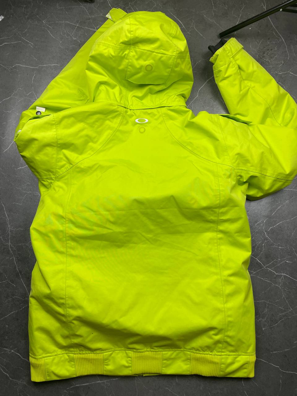 Oakley lime green ski jacket with hood, multicolored interior lining, logo on chest.