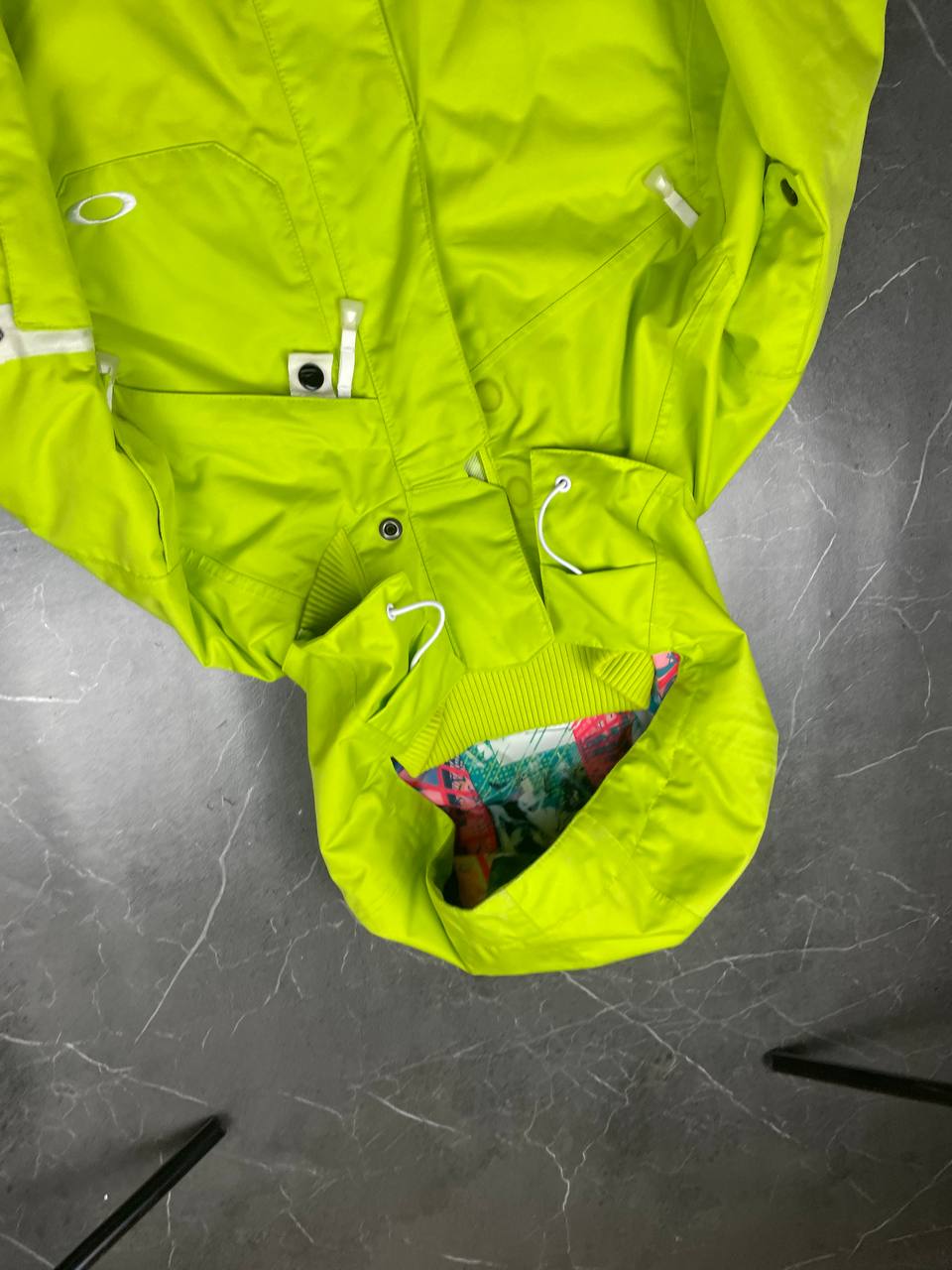 Oakley lime green ski jacket with hood, multicolored interior lining, logo on chest.