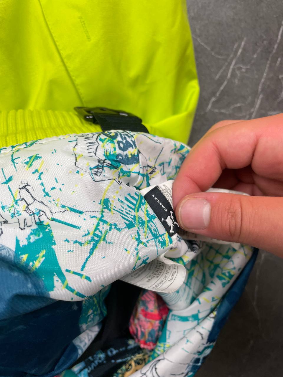 Oakley lime green ski jacket with hood, multicolored interior lining, logo on chest.