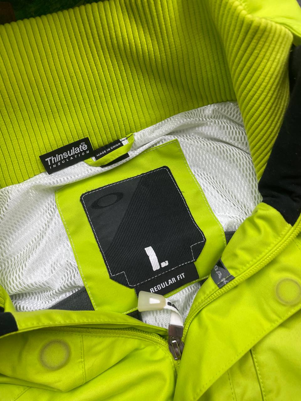 Oakley lime green ski jacket with hood, multicolored interior lining, logo on chest.