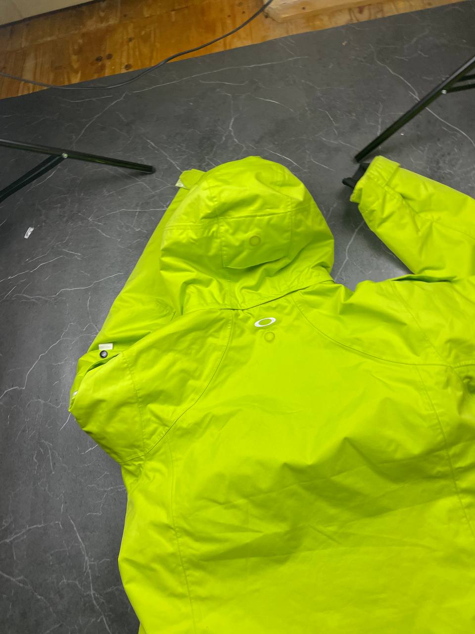Oakley lime green ski jacket with hood, multicolored interior lining, logo on chest.