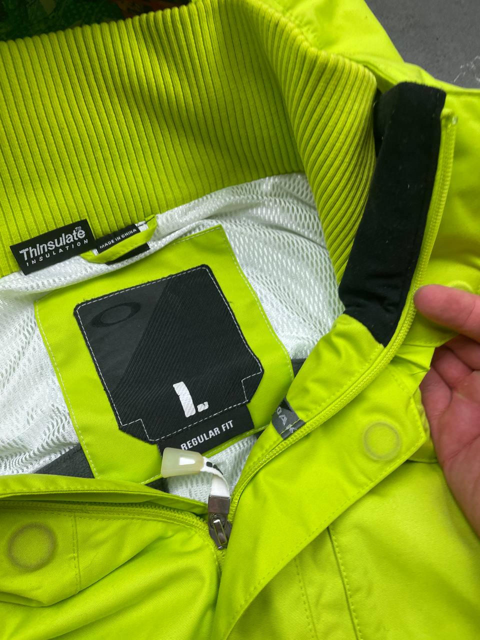 Oakley lime green ski jacket with hood, multicolored interior lining, logo on chest.