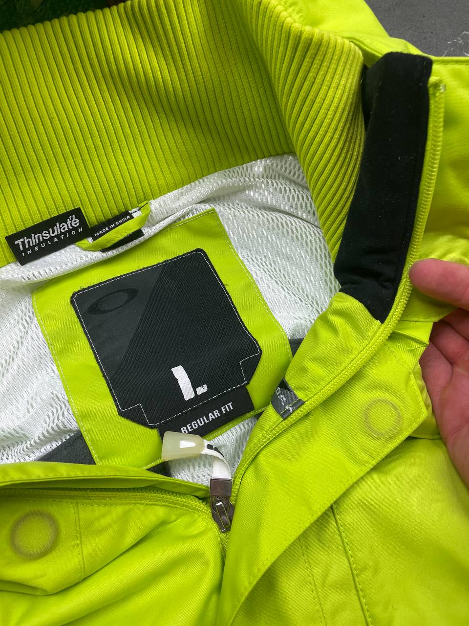 Oakley lime green ski jacket with hood, multicolored interior lining, logo on chest.