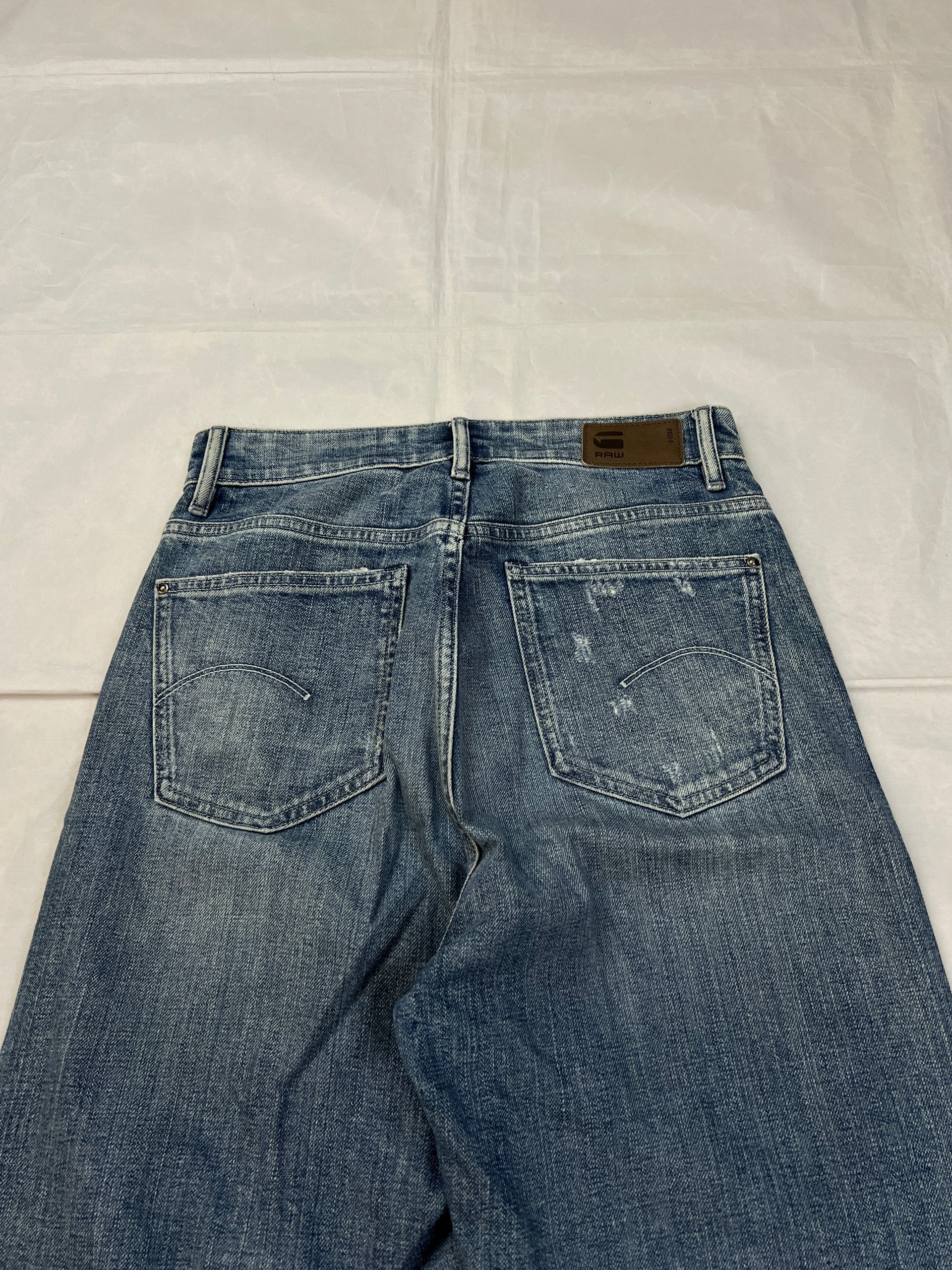 G-Star Raw blue distressed denim jeans with frayed hems and slit detail.