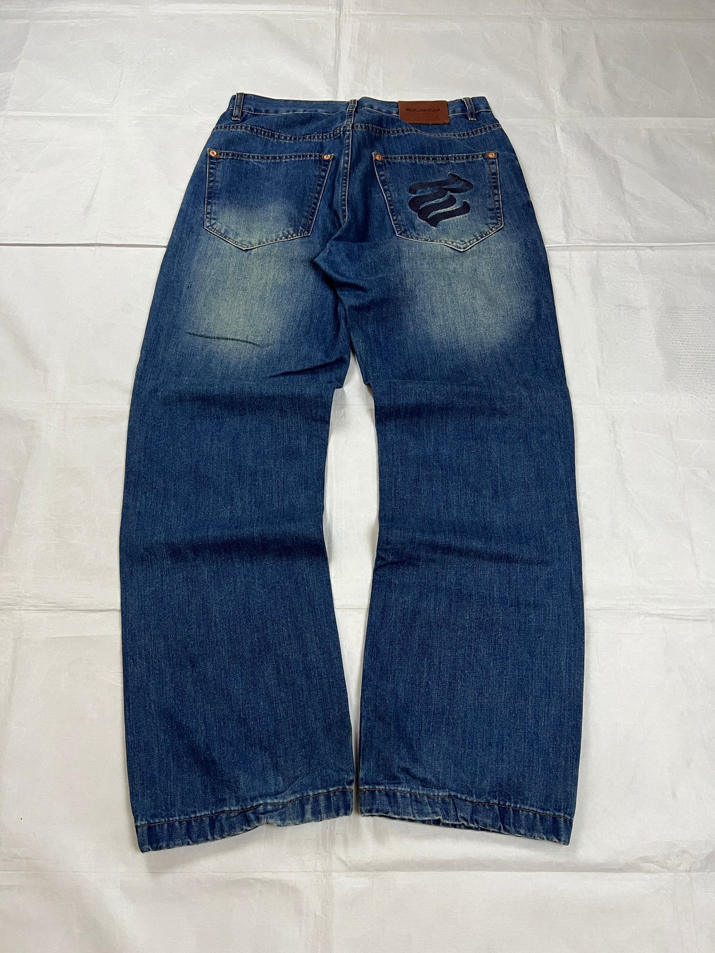 Rocawear blue denim loose fit jeans with faded effect and embroidered back pocket details.