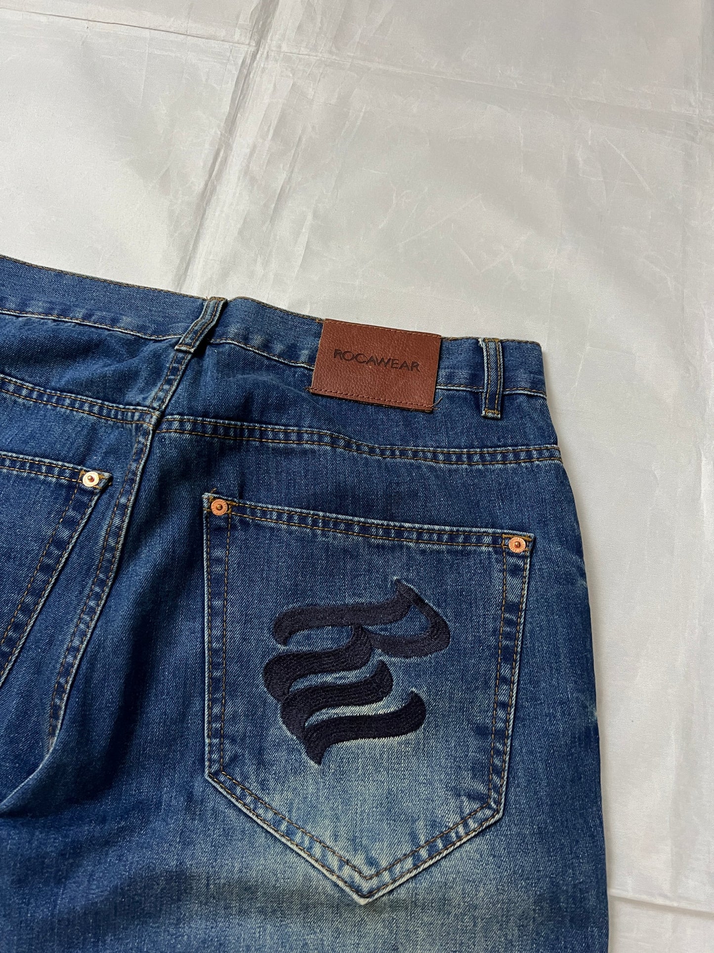 Rocawear blue denim loose fit jeans with faded effect and embroidered back pocket details.