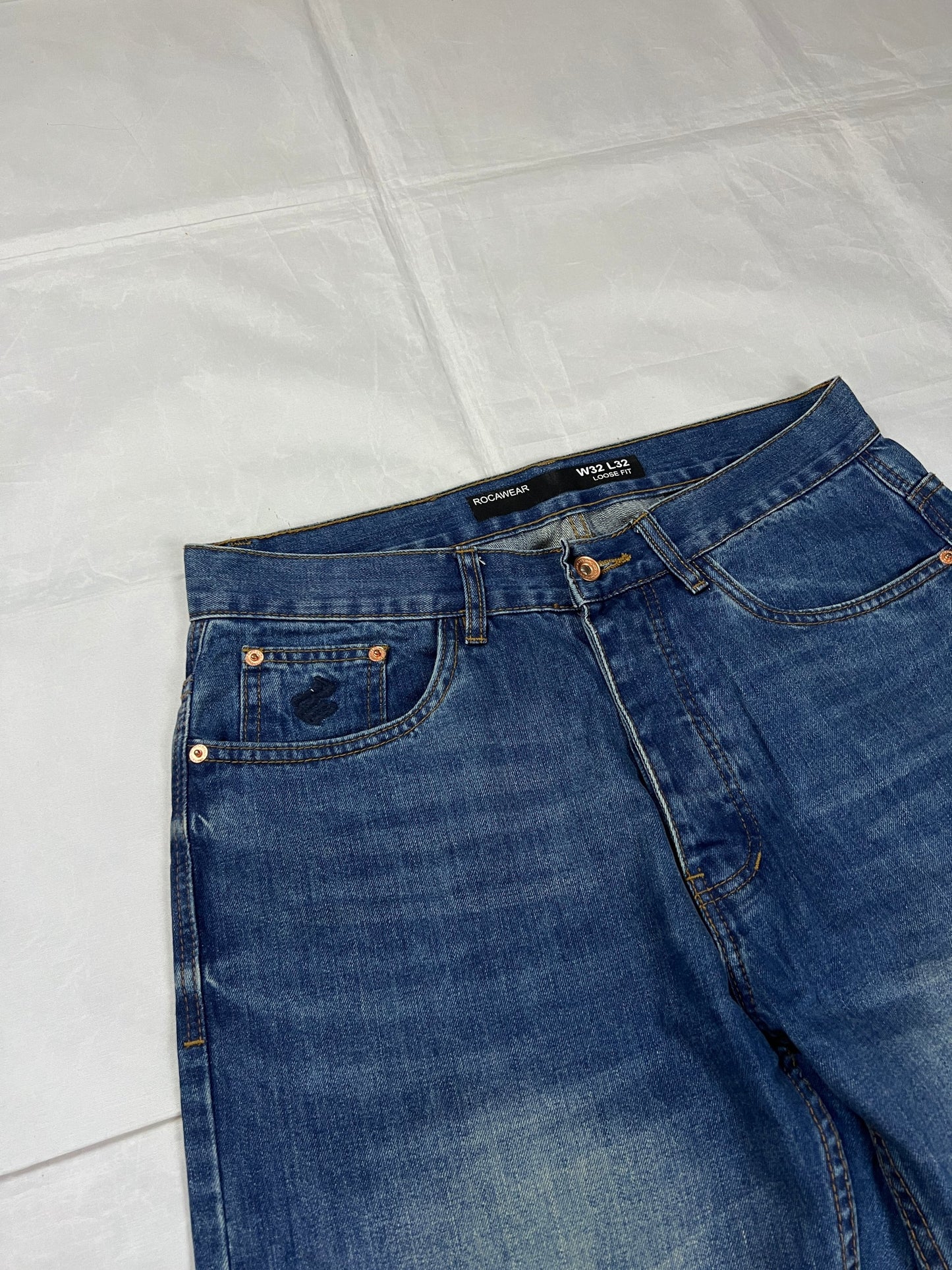 Rocawear blue denim loose fit jeans with faded effect and embroidered back pocket details.