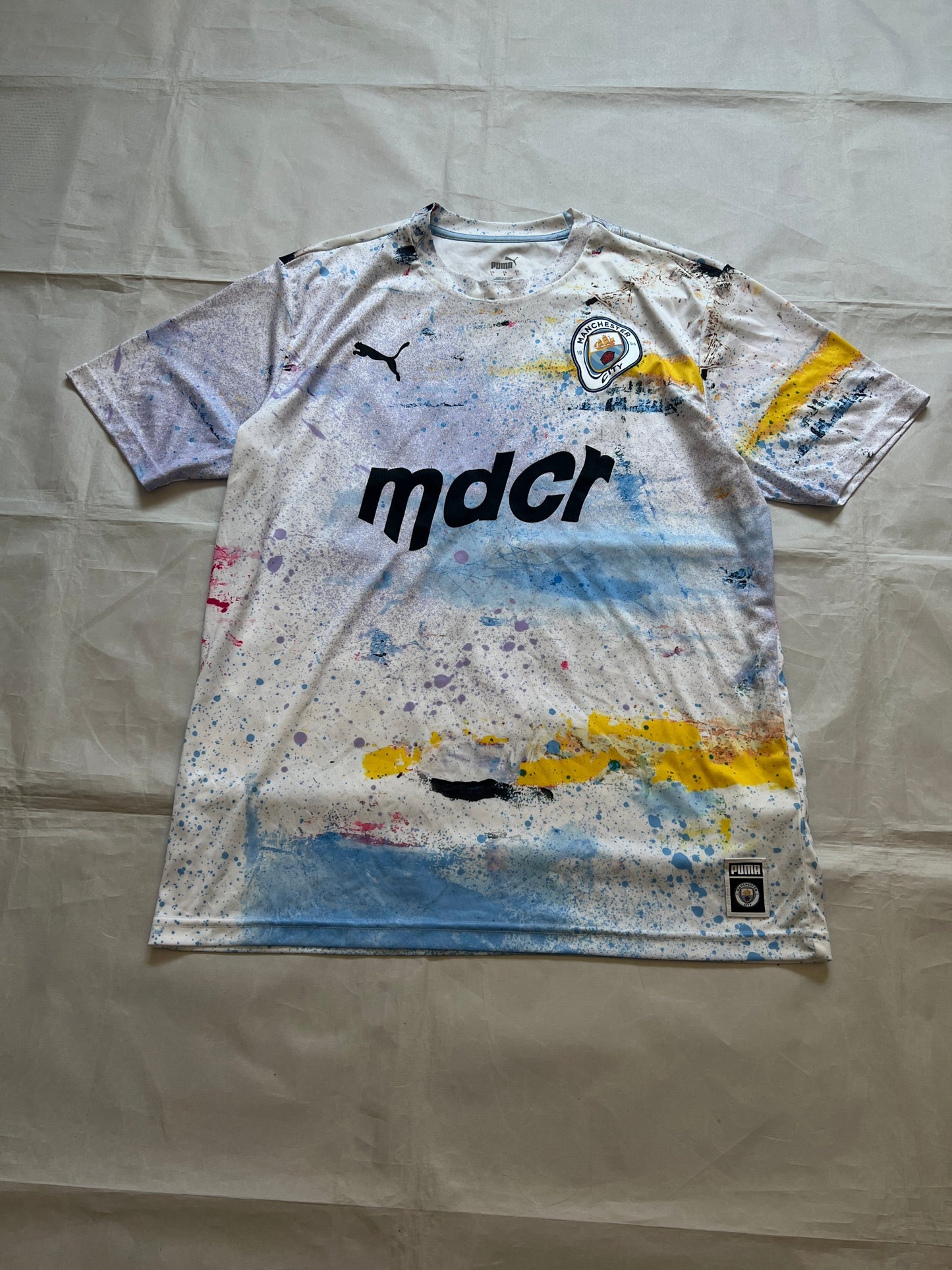 Puma blue and white football jersey with Manchester City crest and splatter paint design.