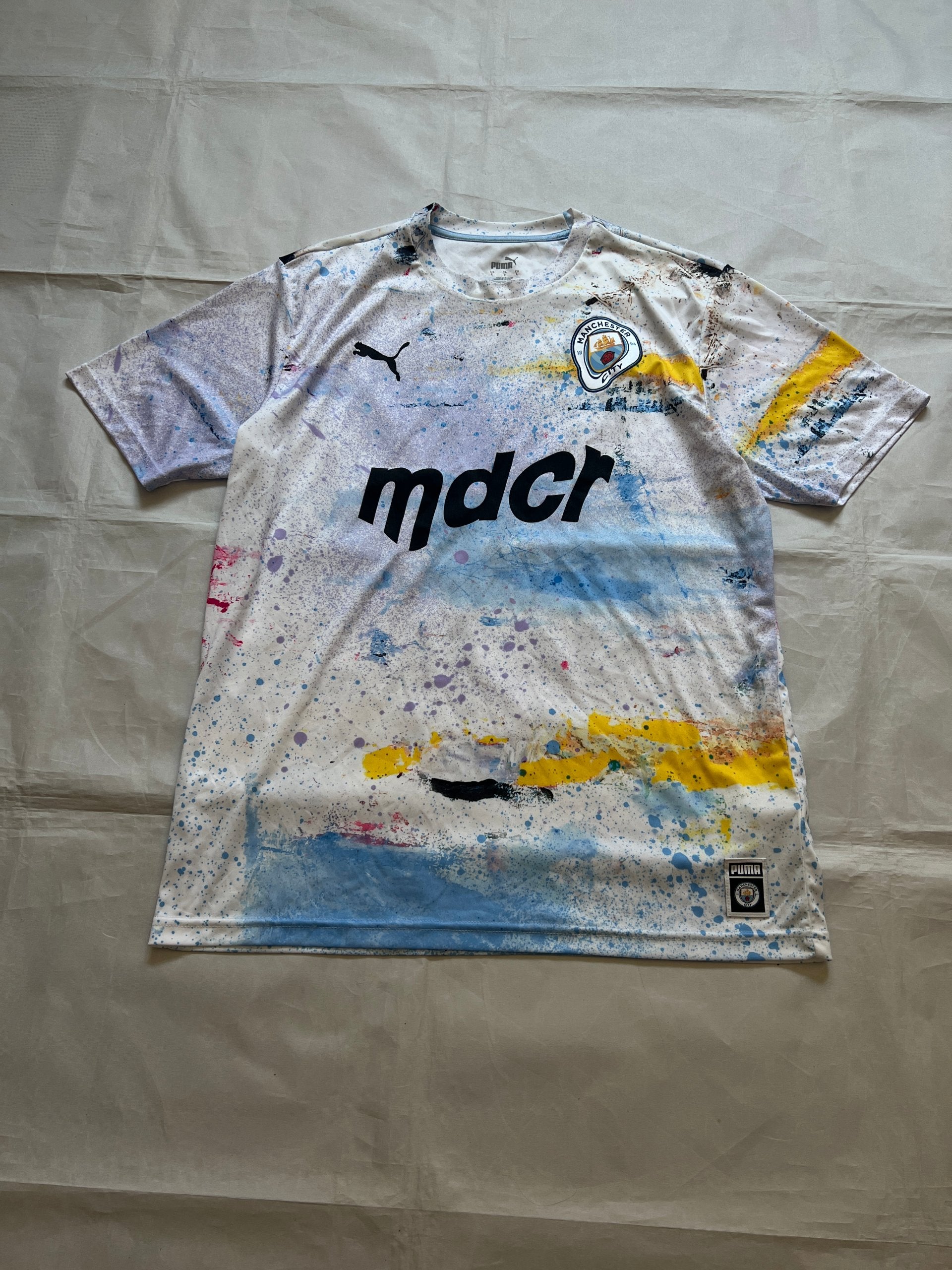 Puma blue and white football jersey with Manchester City crest and splatter paint design.