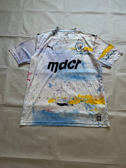 Puma blue and white football jersey with Manchester City crest and splatter paint design.