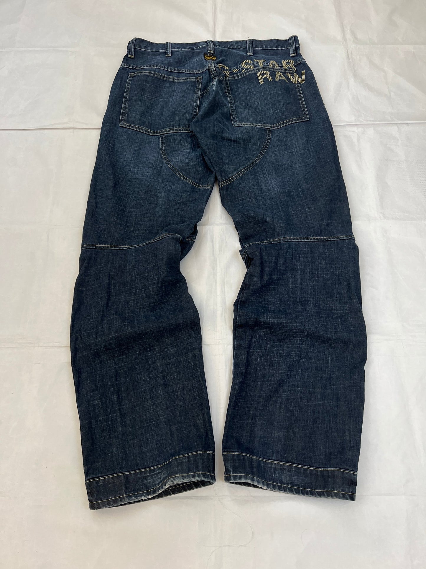 G-Star Raw blue denim jeans with embroidered logo, distinctive seam detailing, and large back pockets.