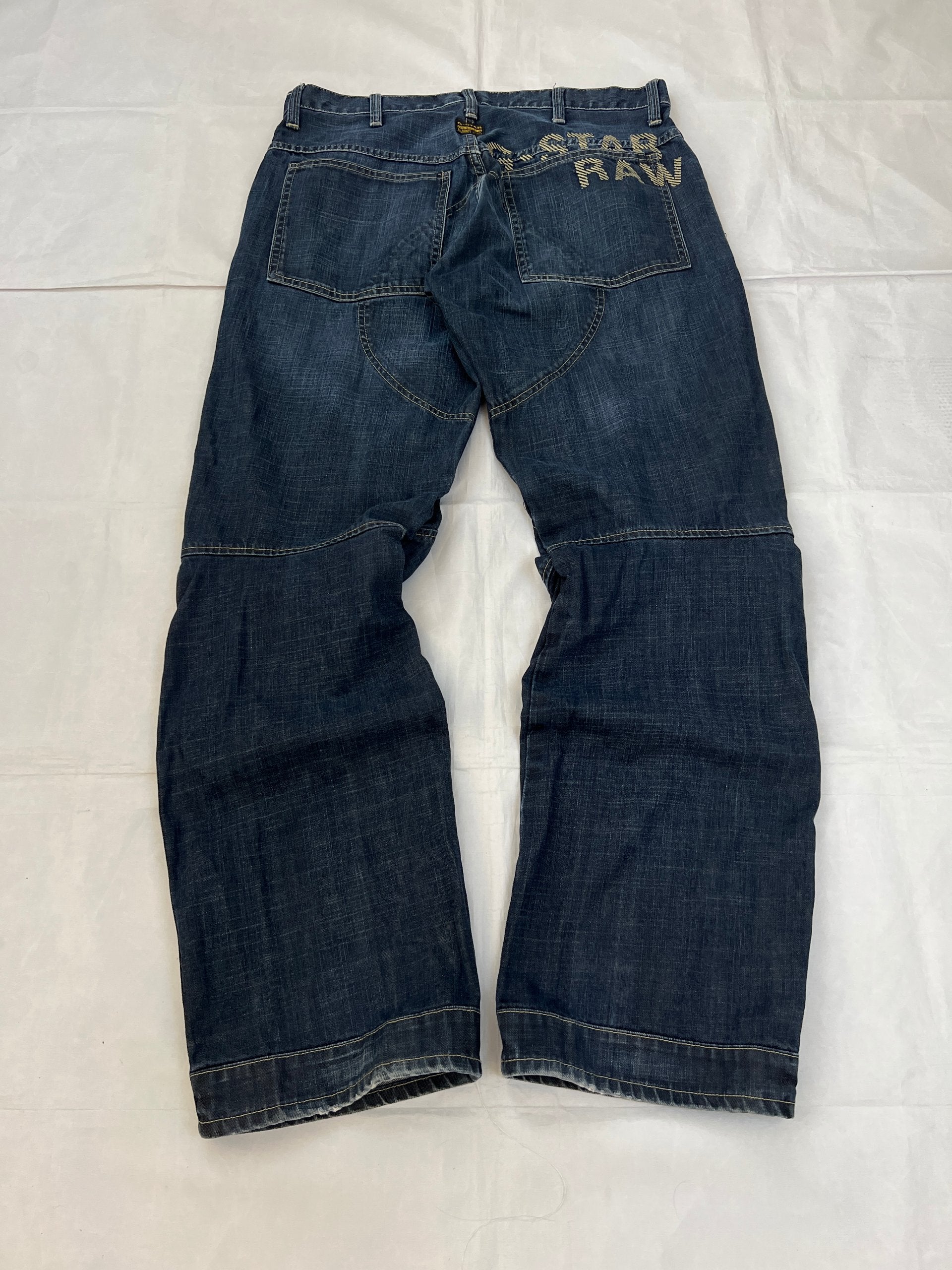 G-Star Raw blue denim jeans with embroidered logo, distinctive seam detailing, and large back pockets.
