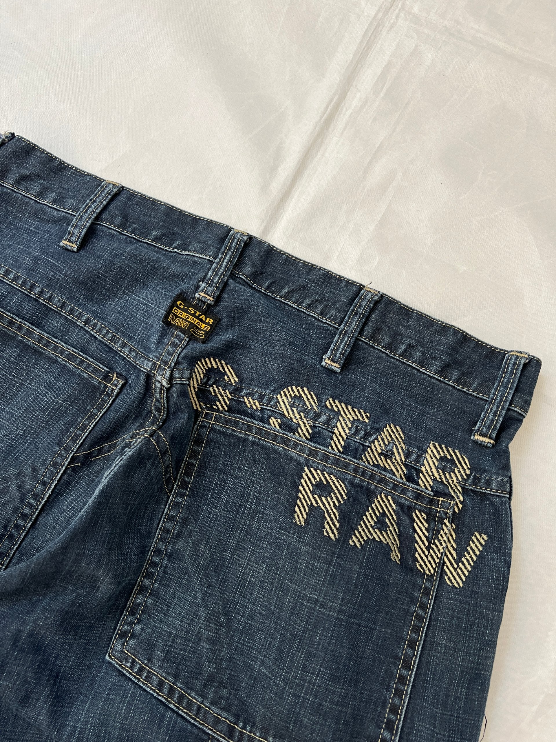 G-Star Raw blue denim jeans with embroidered logo, distinctive seam detailing, and large back pockets.