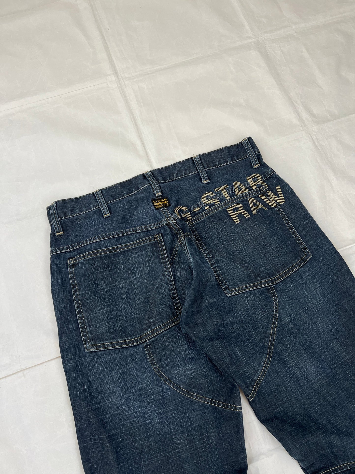 G-Star Raw blue denim jeans with embroidered logo, distinctive seam detailing, and large back pockets.