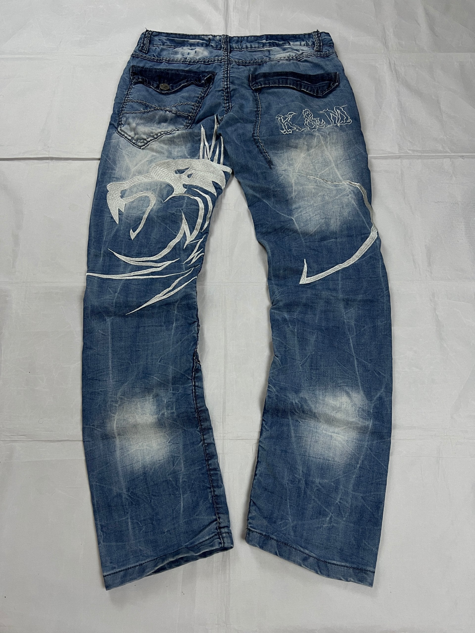 KJM blue denim jeans with white embroidered lion and logo, patchwork stitch detailing.
