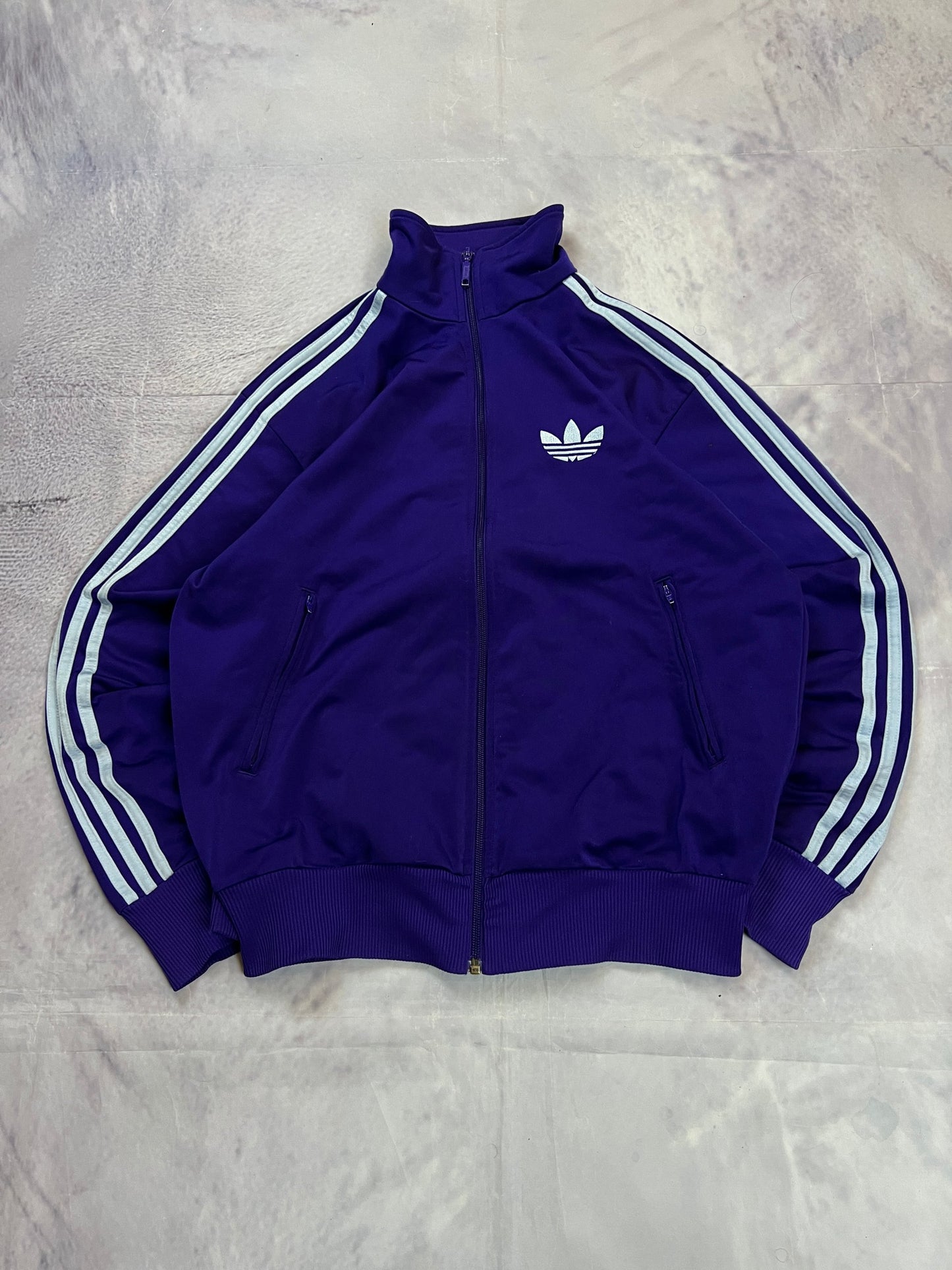 Adidas men's purple track jacket with embroidered logo and white stripes on sleeves.