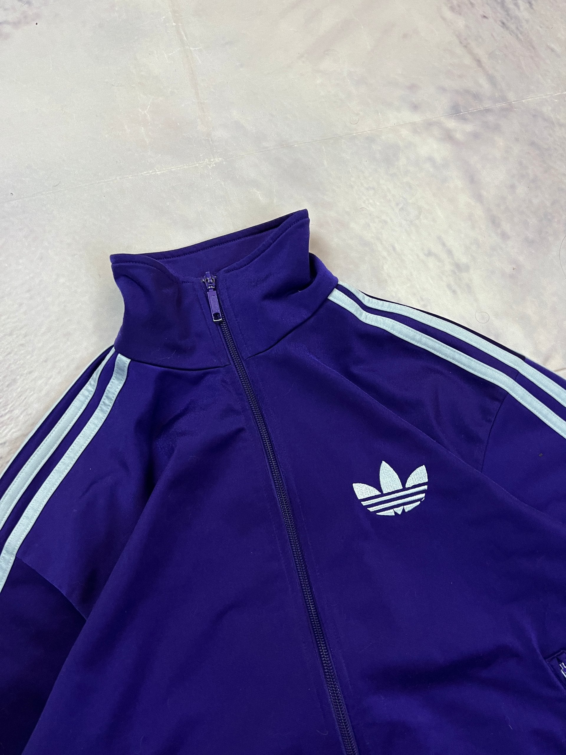 Adidas men's purple track jacket with embroidered logo and white stripes on sleeves.