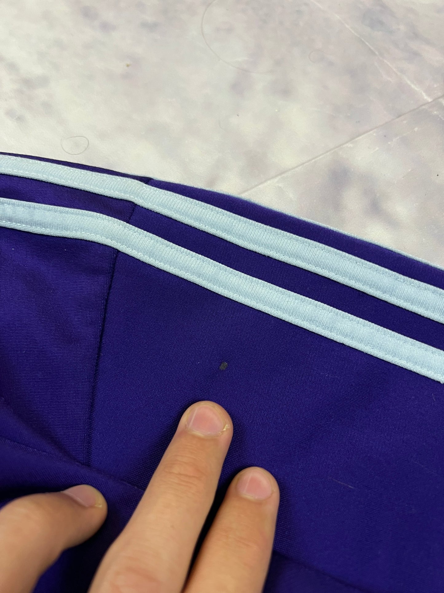 Adidas men's purple track jacket with embroidered logo and white stripes on sleeves.