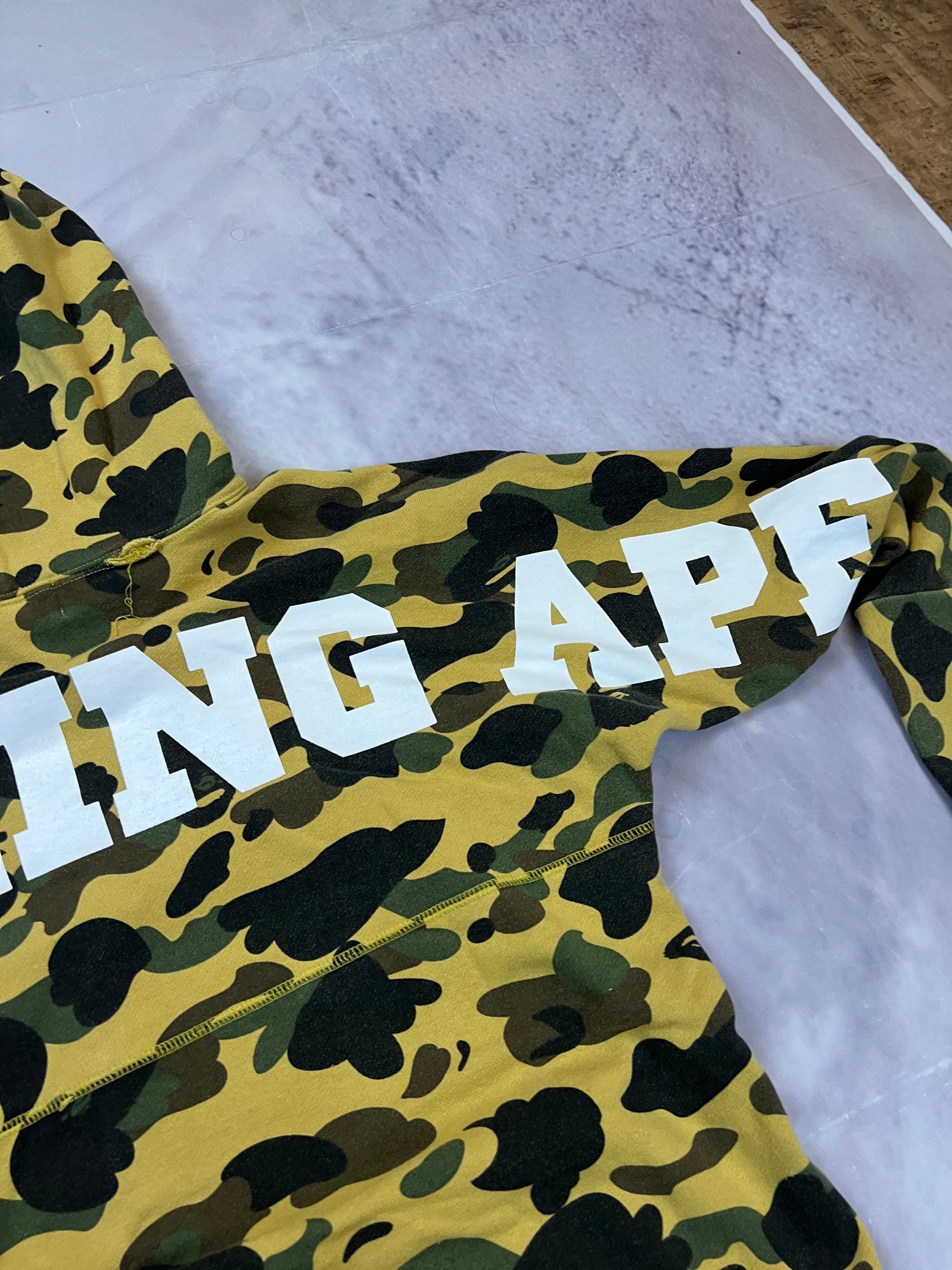A Bathing Ape black hoodie yellow and green camo pattern with white ape head logo.