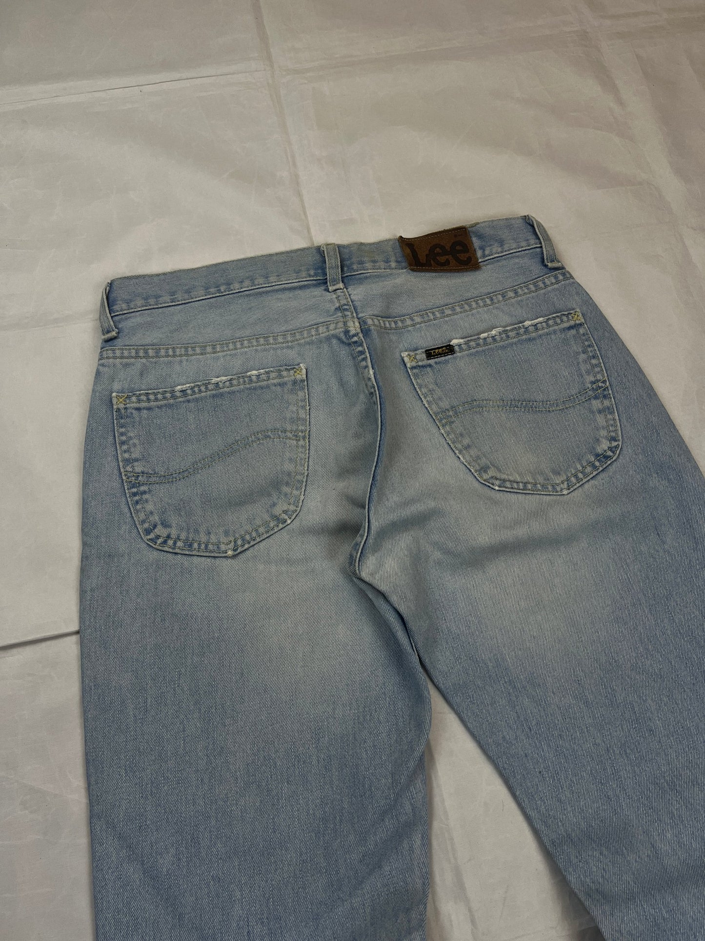 Lee light blue flared jeans with leather patch, five-pocket styling, and frayed hems.