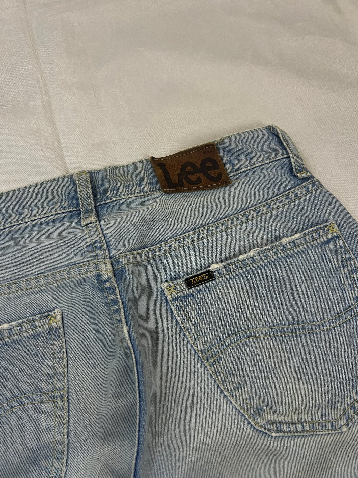 Lee light blue flared jeans with leather patch, five-pocket styling, and frayed hems.