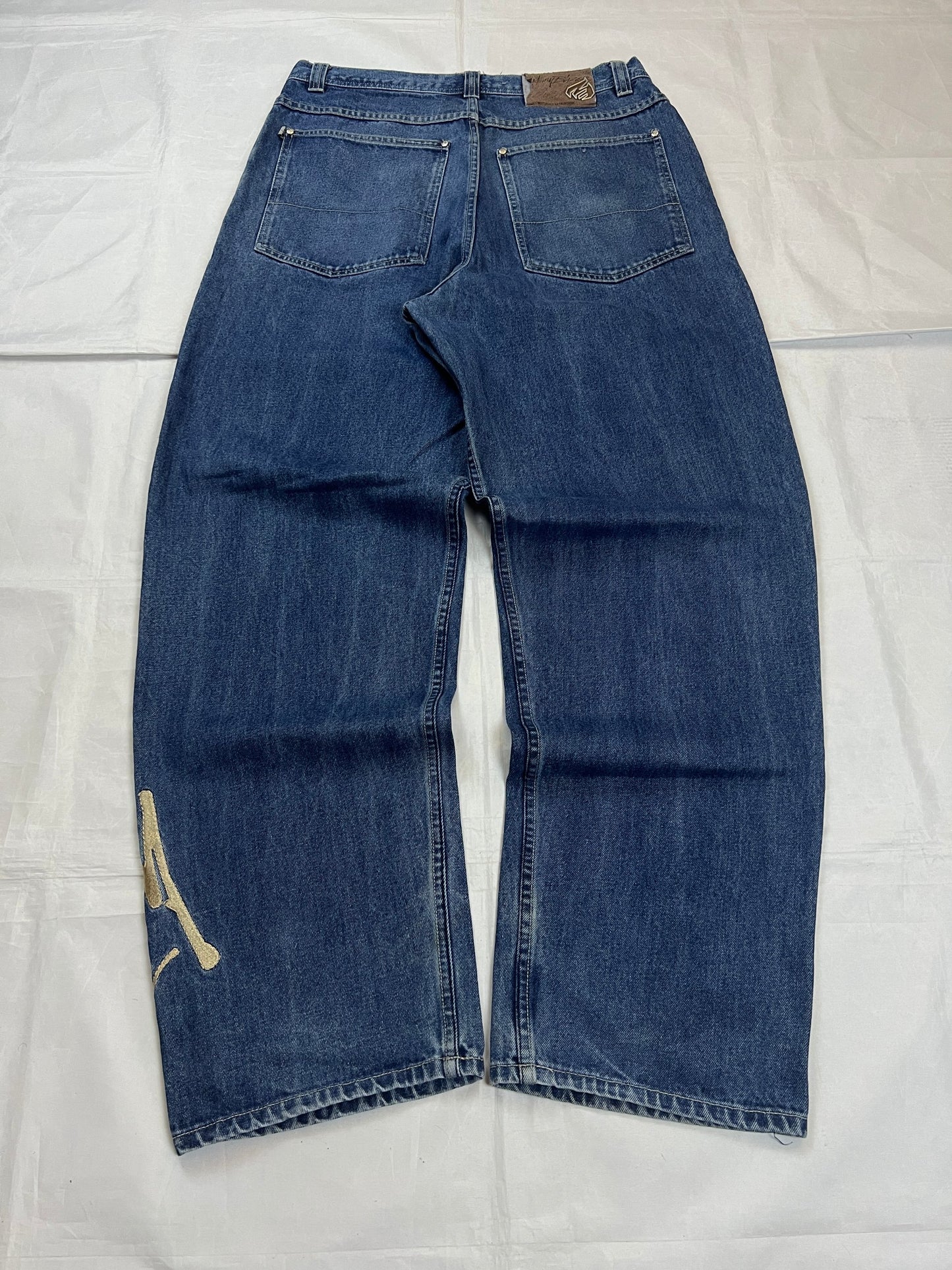 Johnny Blaze blue wide leg jeans with embroidered logo and leather patch on waistband.