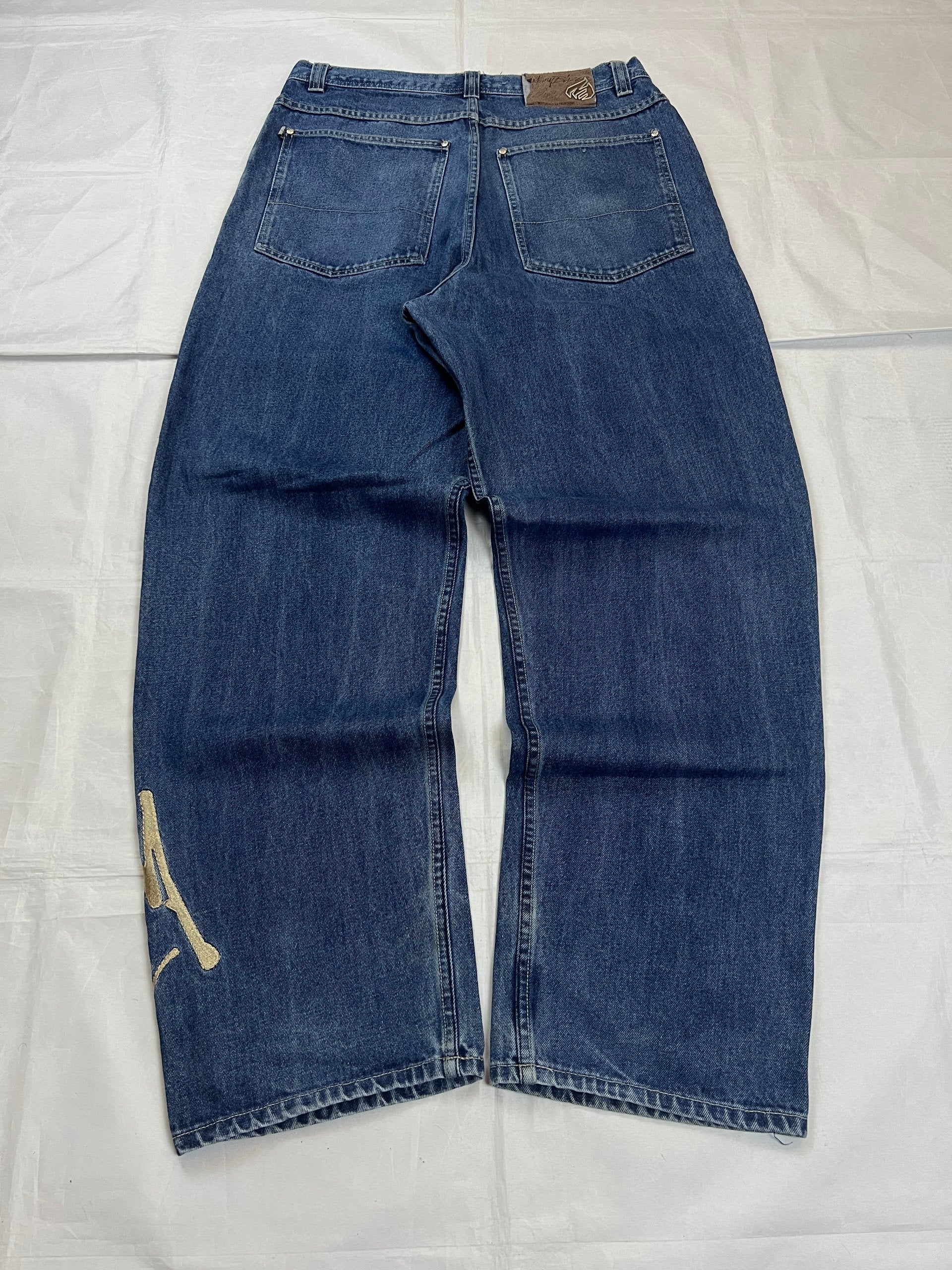 Johnny Blaze blue wide leg jeans with embroidered logo and leather patch on waistband.