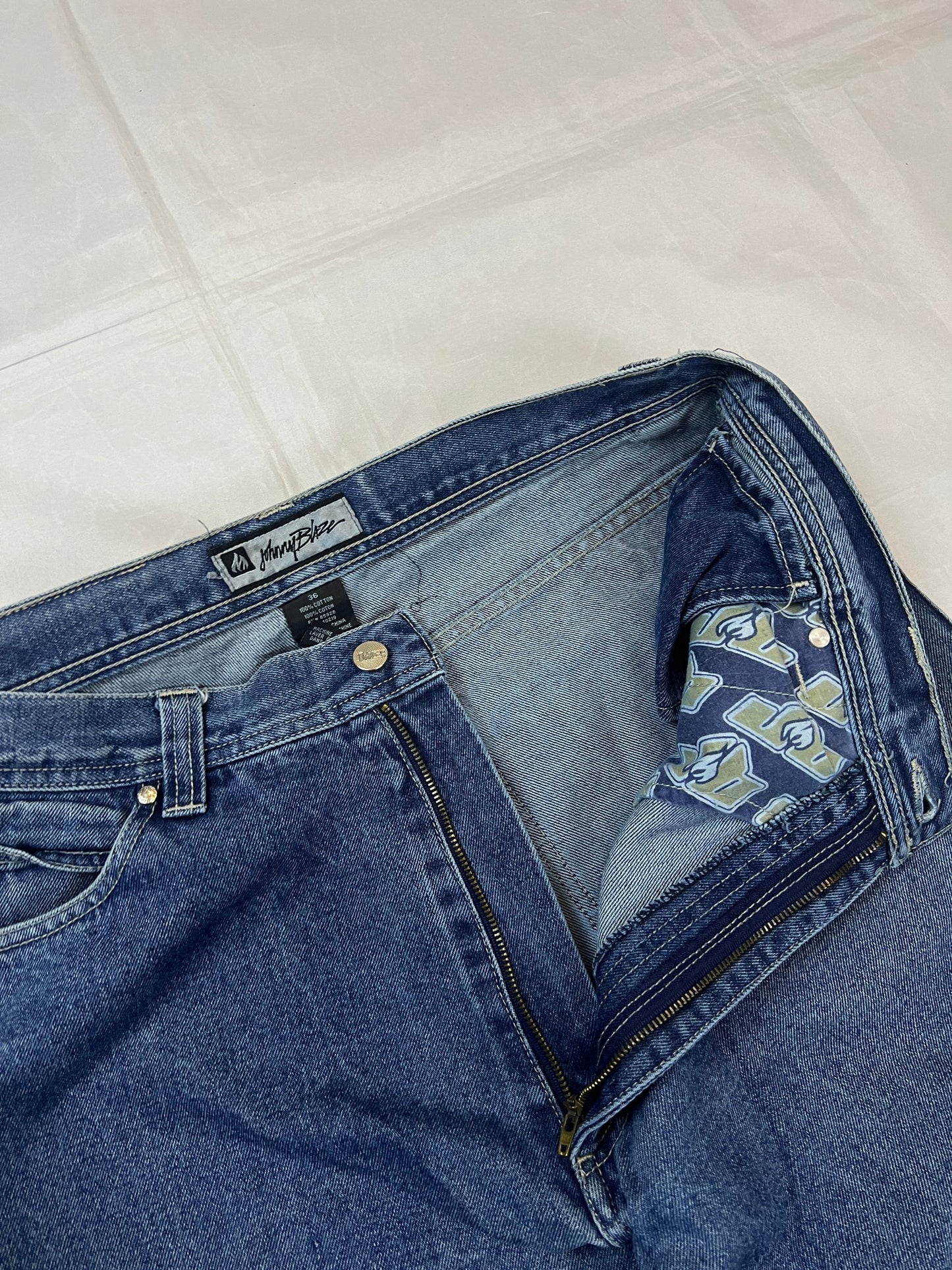 Johnny Blaze blue wide leg jeans with embroidered logo and leather patch on waistband.