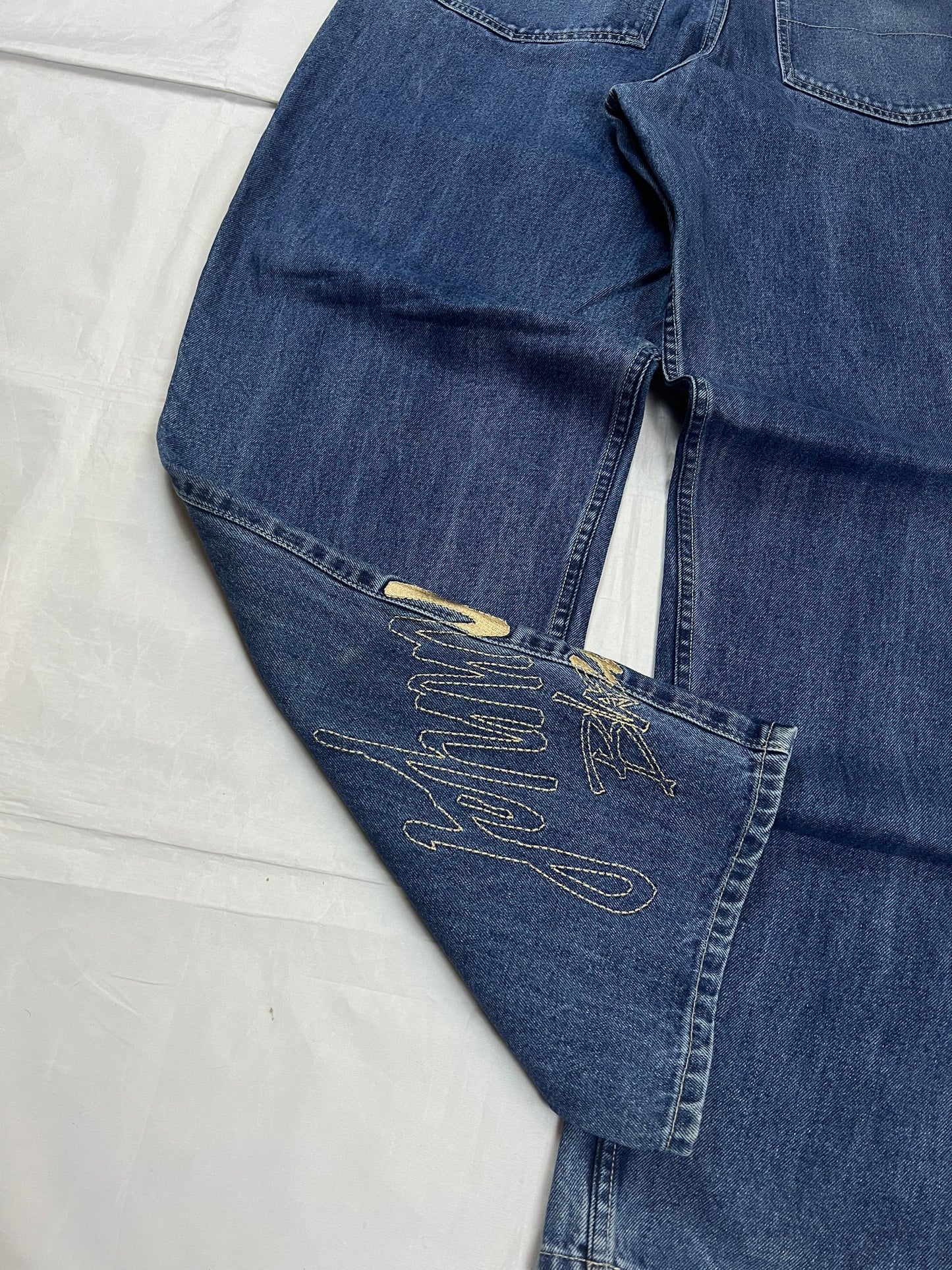 Johnny Blaze blue wide leg jeans with embroidered logo and leather patch on waistband.