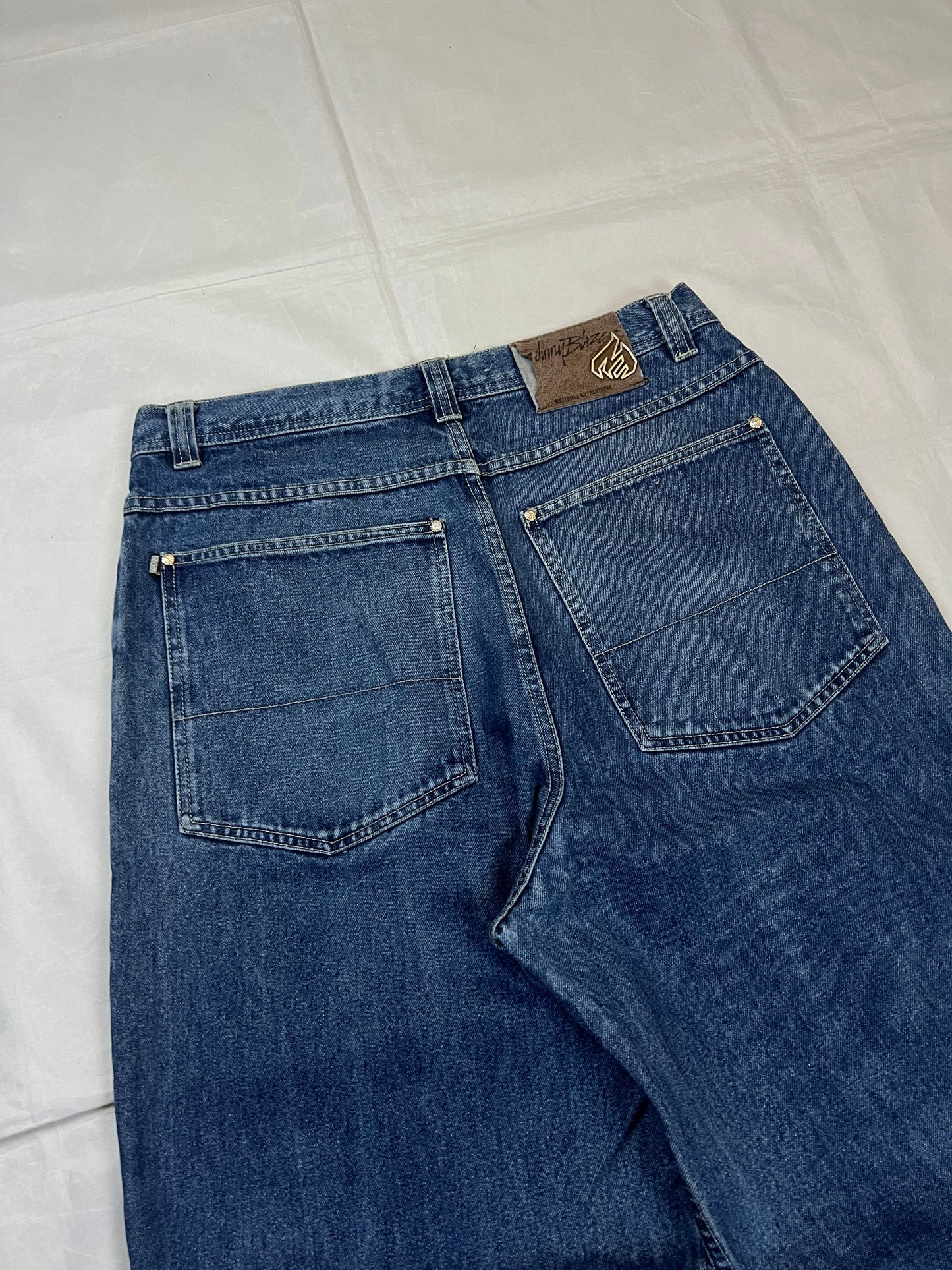 Johnny Blaze blue wide leg jeans with embroidered logo and leather patch on waistband.