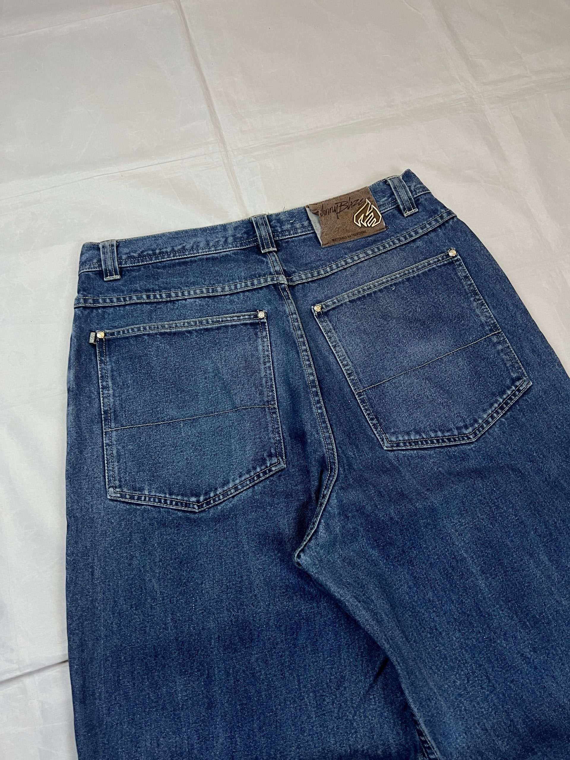 Johnny Blaze blue wide leg jeans with embroidered logo and leather patch on waistband.