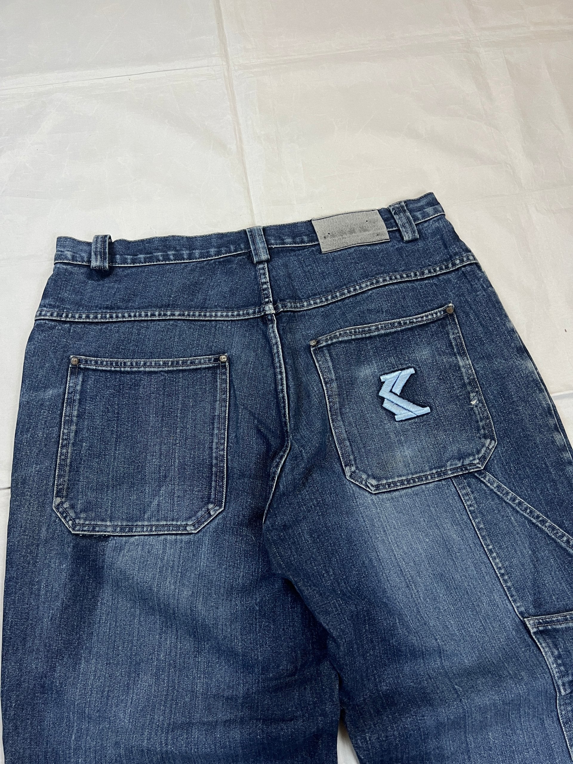 Kani blue denim carpenter jeans with distressed details, faded wash, and patch pockets.