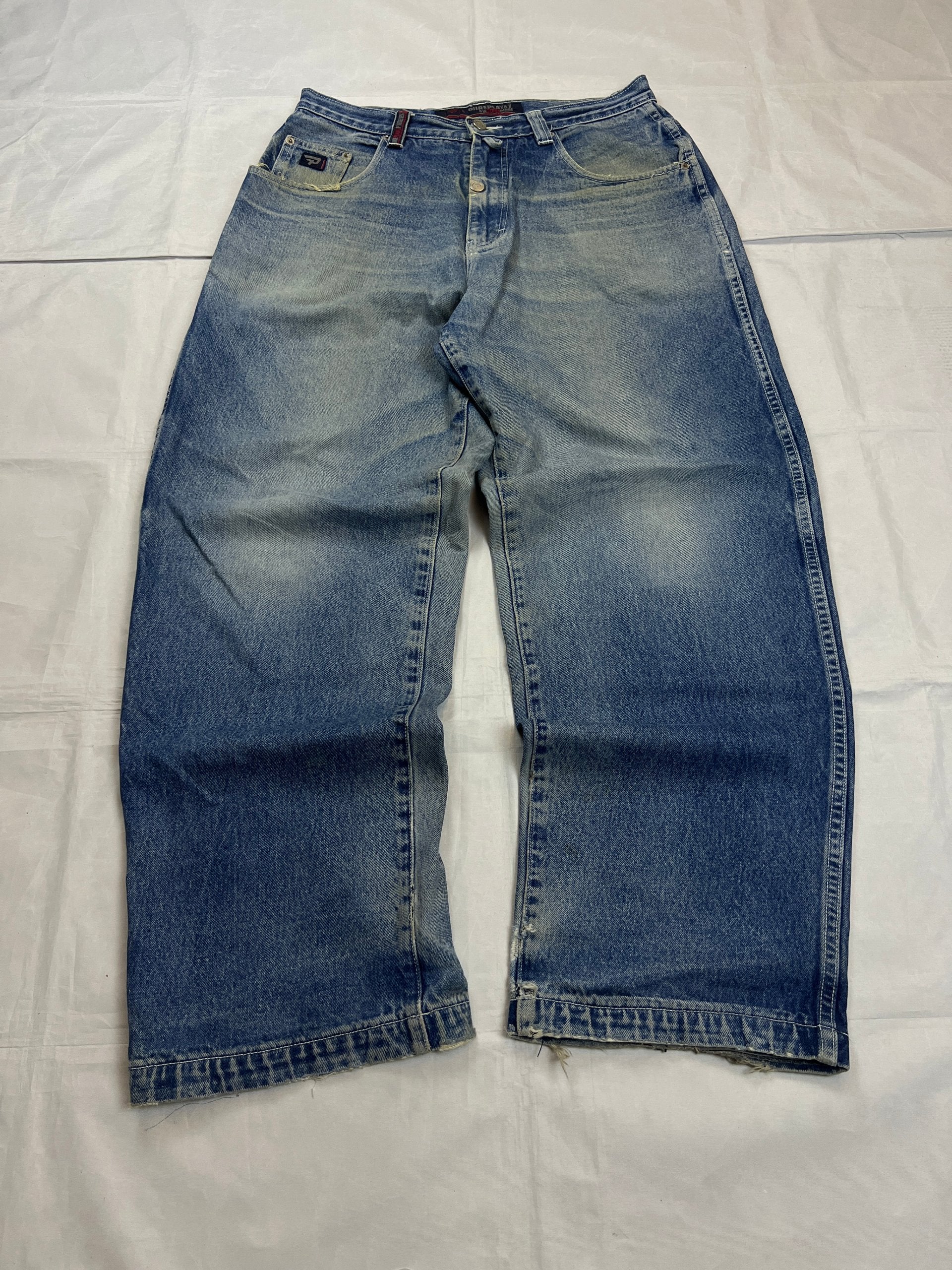 Pure Playaz blue denim jeans with distressed rips, faded wash, and branded patches.