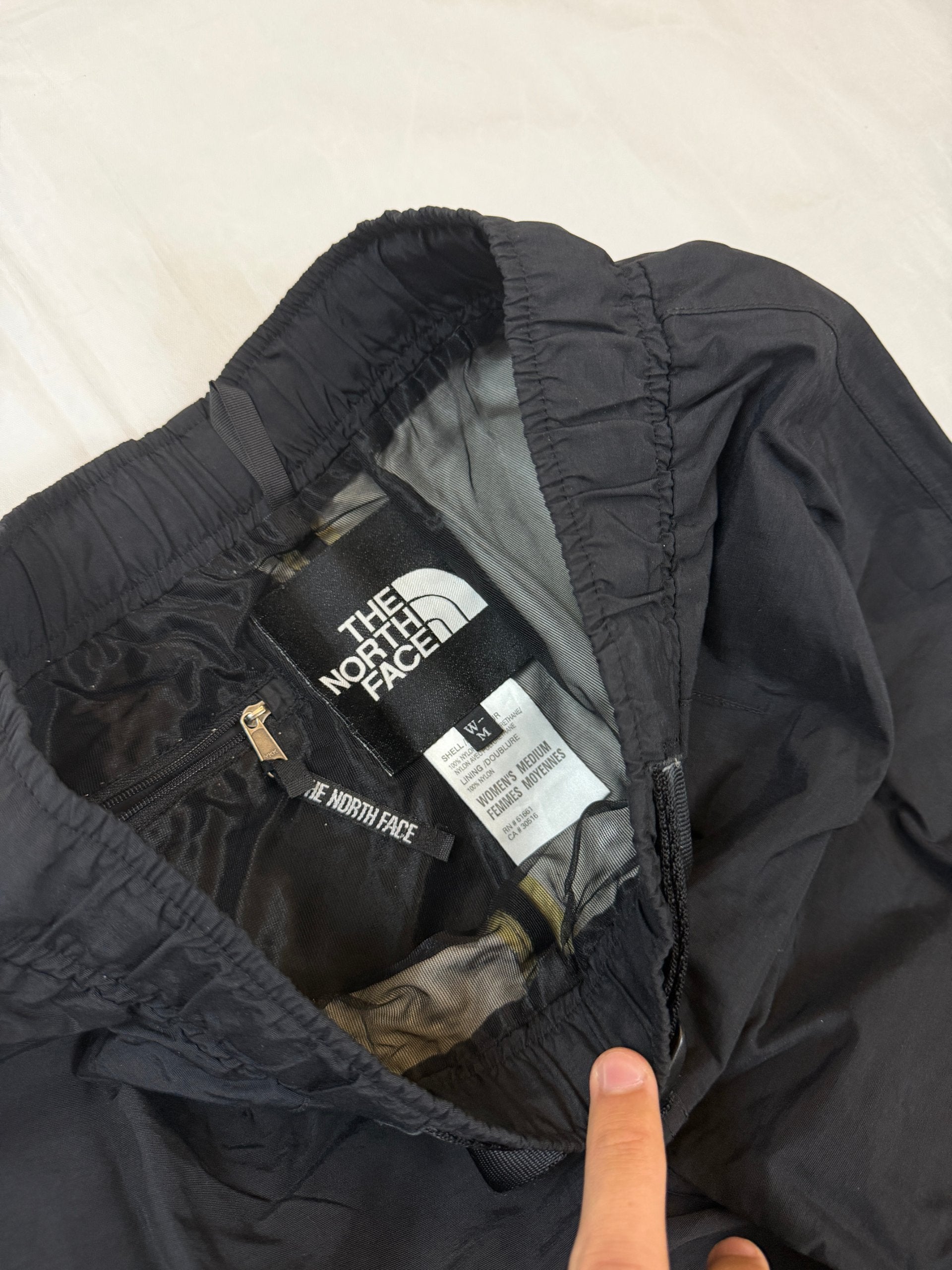 The North Face black hiking trousers with embroidered logo and adjustable Velcro ankle closures.