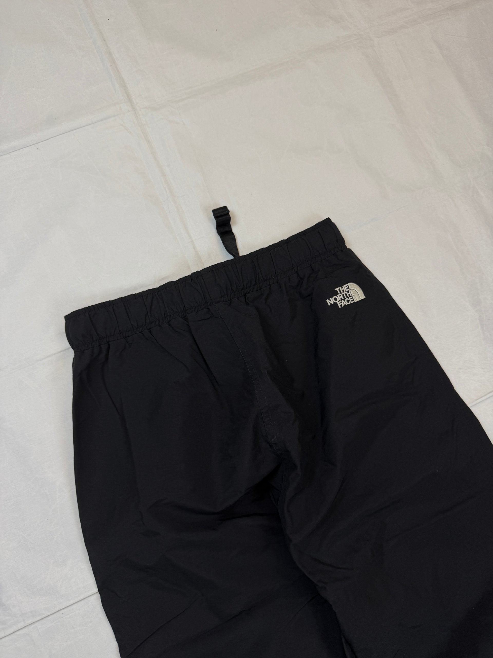 The North Face black hiking trousers with embroidered logo and adjustable Velcro ankle closures.