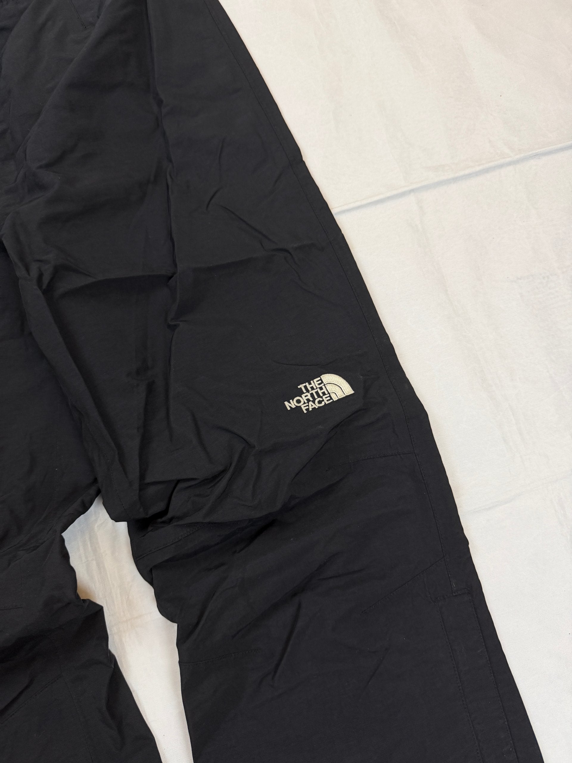 The North Face black hiking trousers with embroidered logo and adjustable Velcro ankle closures.