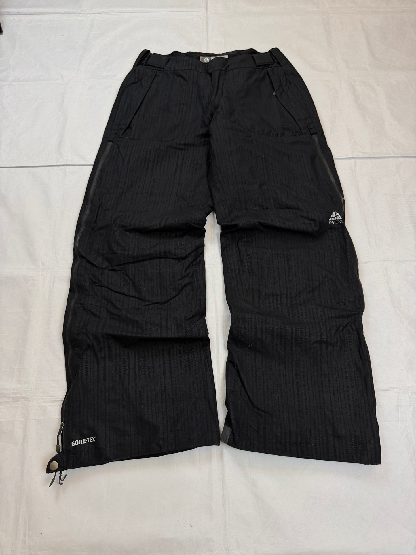 Nike black snow pants with ACG and Gore-Tex logos, adjustable waist, zippered vents.