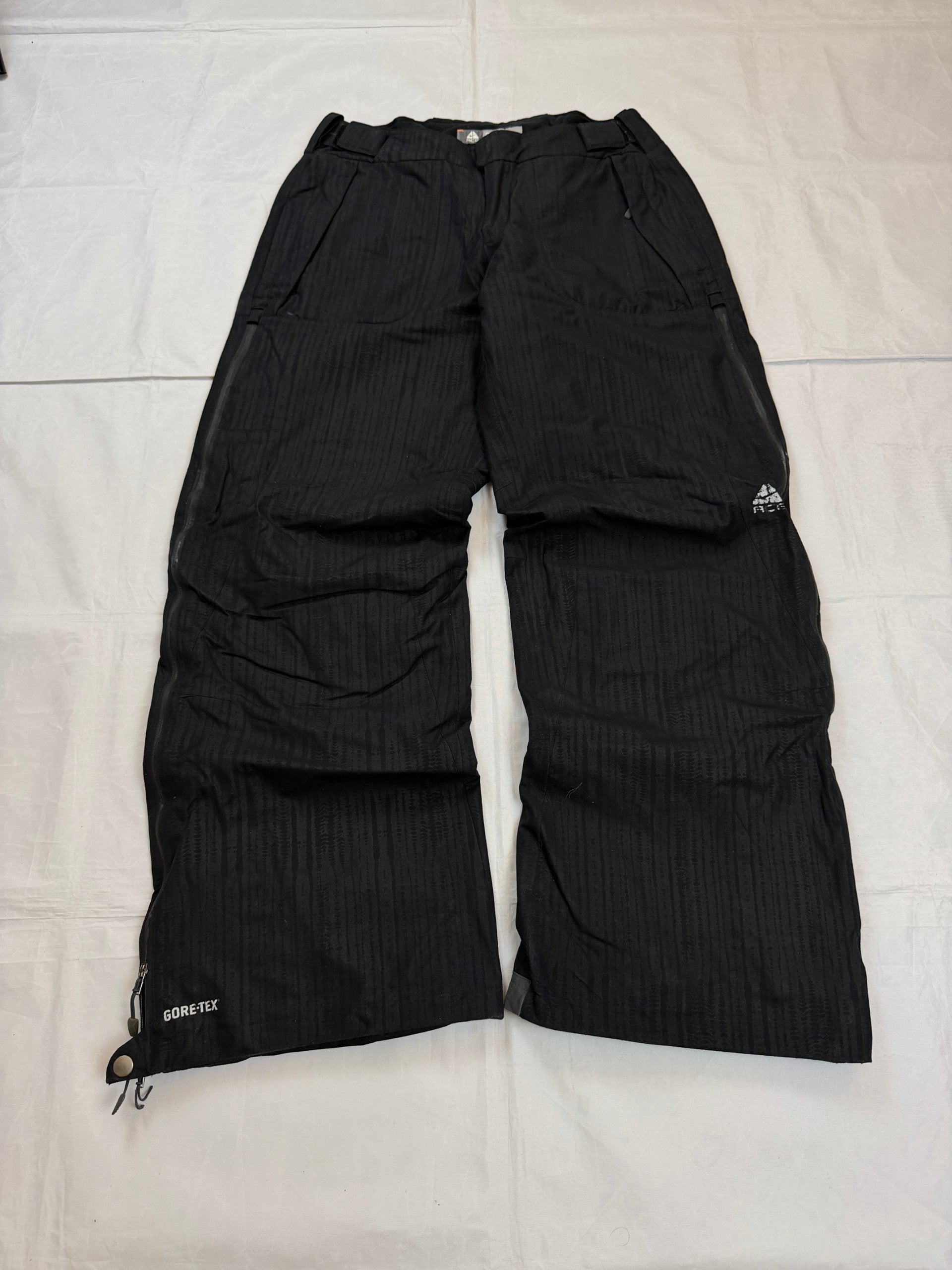 Nike black snow pants with ACG and Gore-Tex logos, adjustable waist, zippered vents.