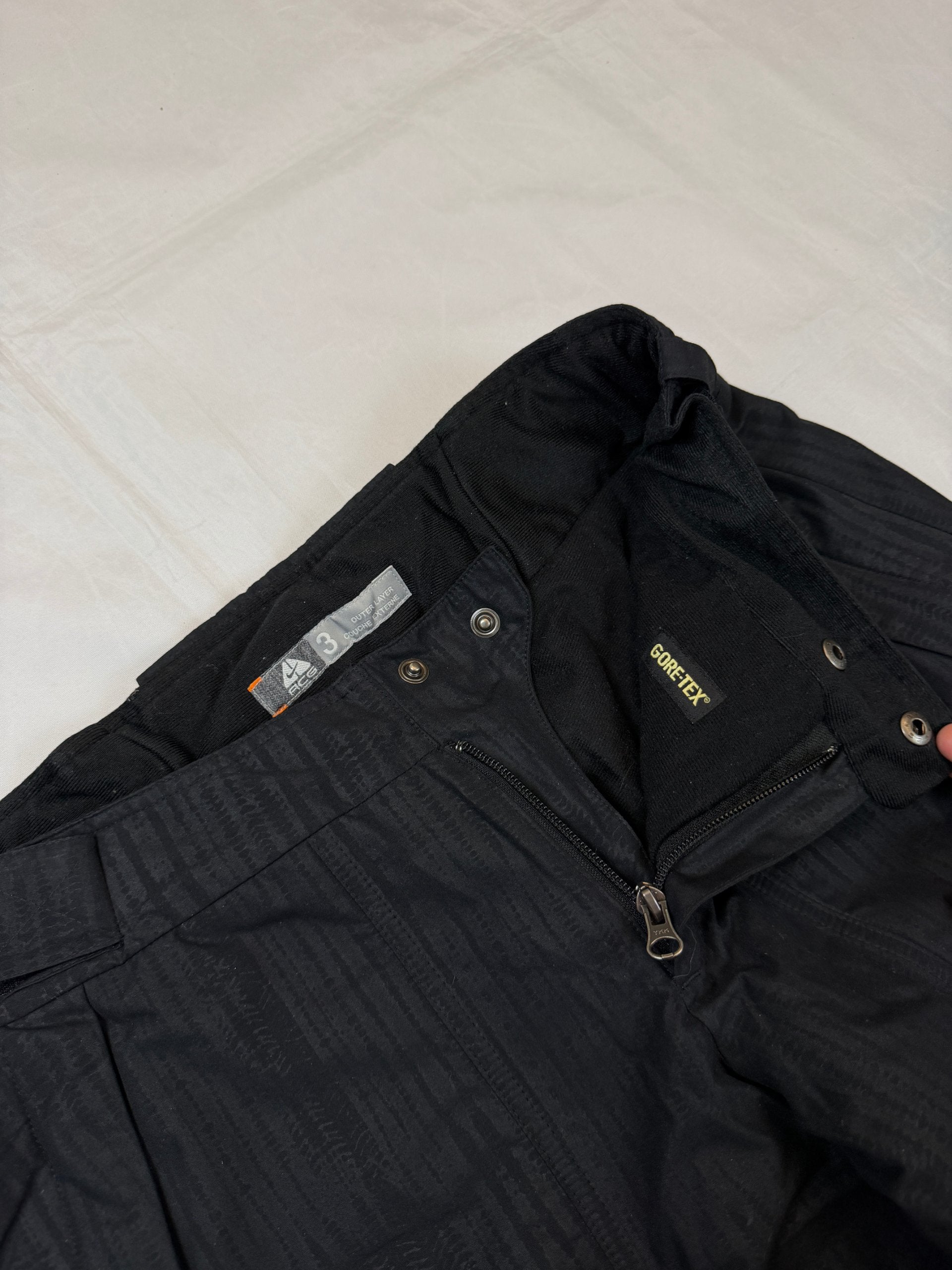 Nike black snow pants with ACG and Gore-Tex logos, adjustable waist, zippered vents.