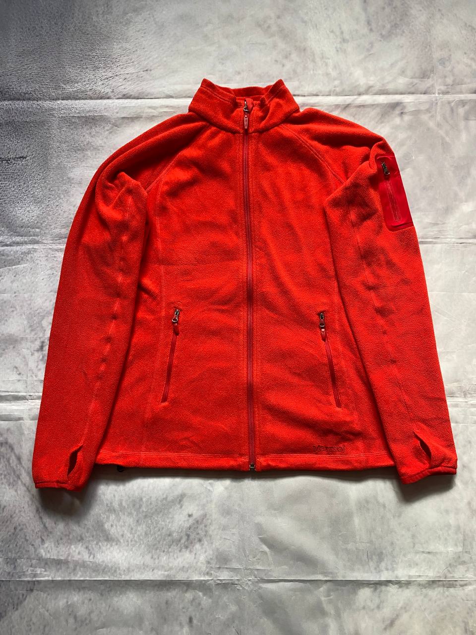 Marmot red fleece jacket with full zip, thumb holes, and elbow patch detail.