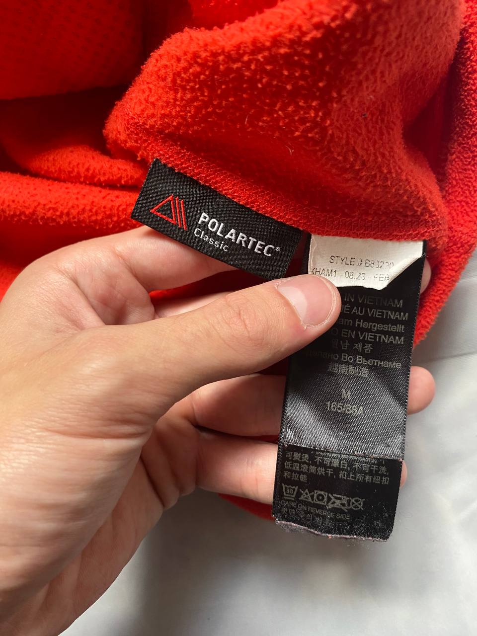 Marmot red fleece jacket with full zip, thumb holes, and elbow patch detail.