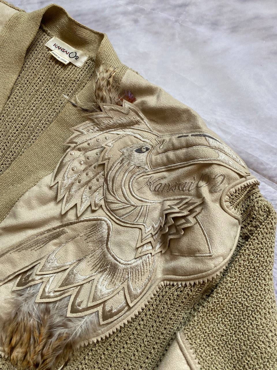 Kansai O2 beige knitted cardigan with embroidered bird detail and fabric patches.