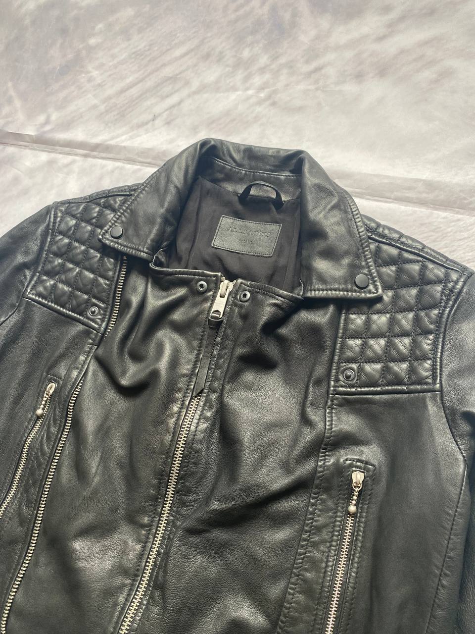 All Saints black quilted leather biker jacket with zippered pockets and adjustable cuffs.